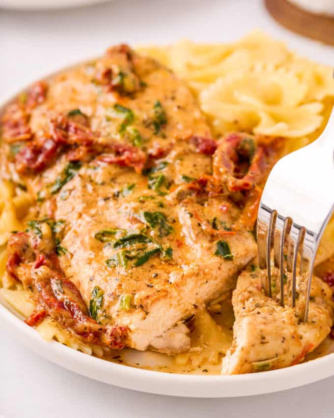 slicing a tuscan chicken breast with a knife and fork