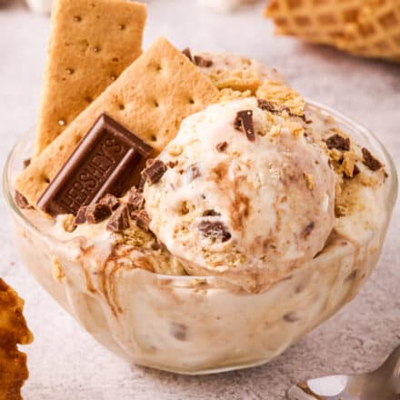 clear bowl of s'mores ice cream garnished with candy bar and graham crackers