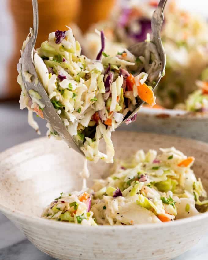 spooning creamy coleslaw into a bowl