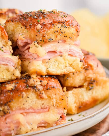 These Baked Ham and Cheese Sliders are made with pillowy and sweet Hawaiian slider buns, savory black forest ham, gooey Swiss cheese, and topped with a buttery honey dijon sauce flecked with onion and poppy seeds! They're the perfect appetizer for game day or any party, and will feed a crowd!