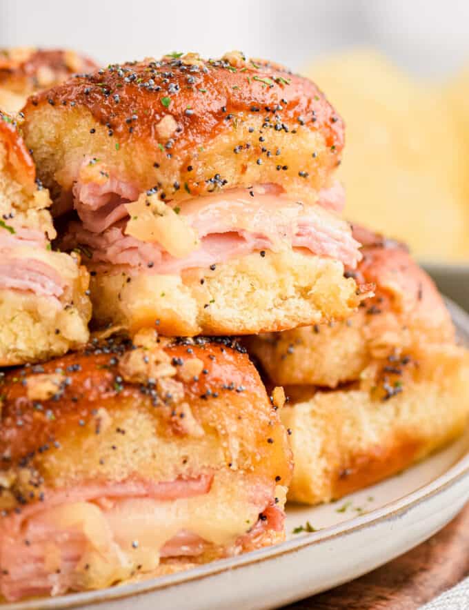 These Baked Ham and Cheese Sliders are made with pillowy and sweet Hawaiian slider buns, savory black forest ham, gooey Swiss cheese, and topped with a buttery honey dijon sauce flecked with onion and poppy seeds! They're the perfect appetizer for game day or any party, and will feed a crowd!