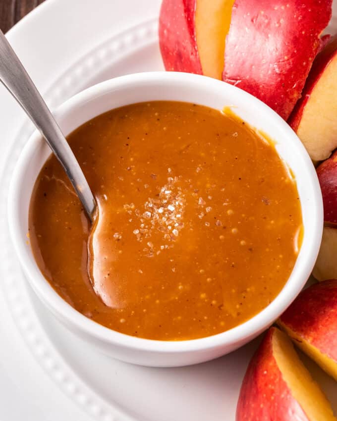 white bowl of caramel sauce with a spoon