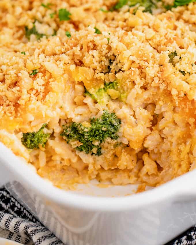 rice casserole with broccoli and cheese in white baking dish with a scoop taken out