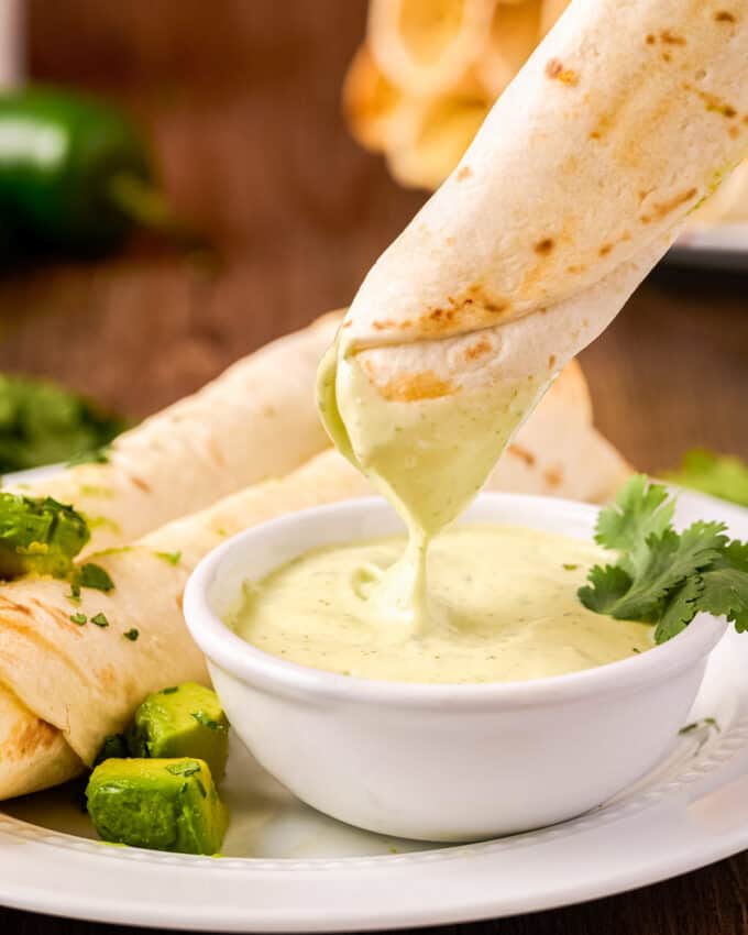 dipping a chicken taquito into avocado cilantro ranch