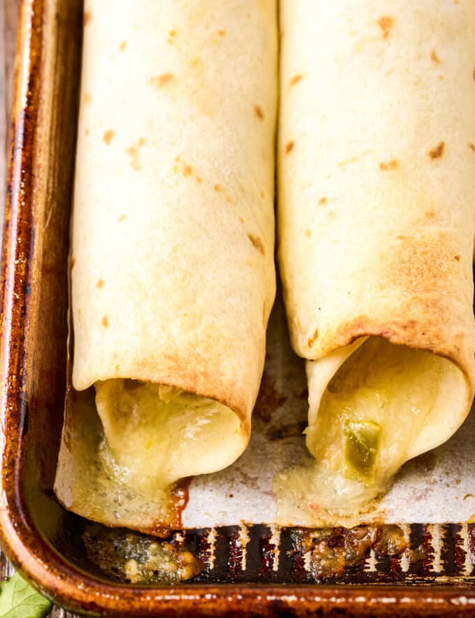crispy baked chicken taquitos on parchment paper lined baking sheet
