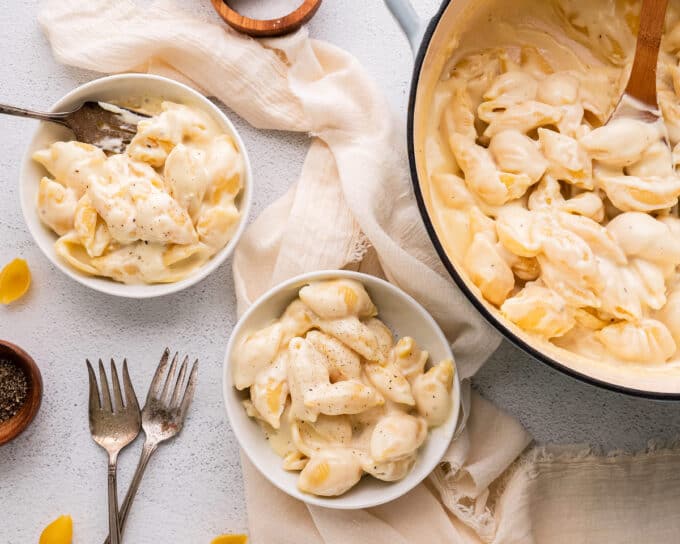 table with dutch oven and two bowls filled with white cheddar mac and cheese