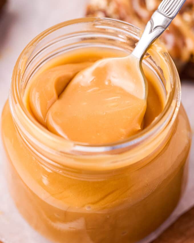 spoon in a jar of caramel sauce