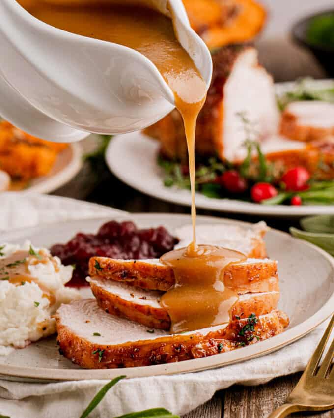 pouring gravy on slices of turkey breast on a plate
