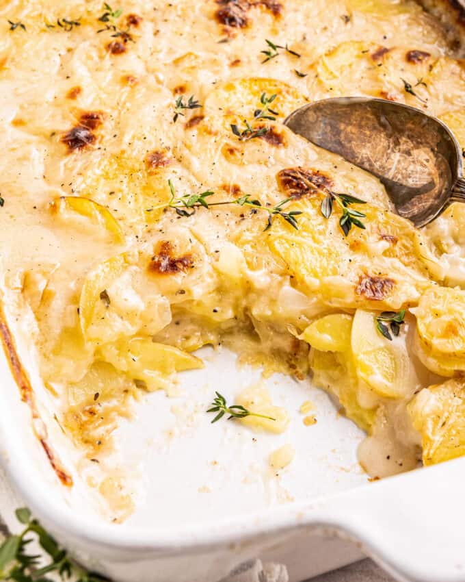 scalloped potatoes with a serving scooped out of the baking dish