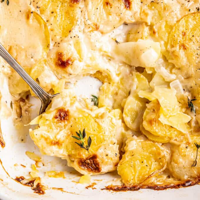 spooning scalloped potatoes out of the baking dish