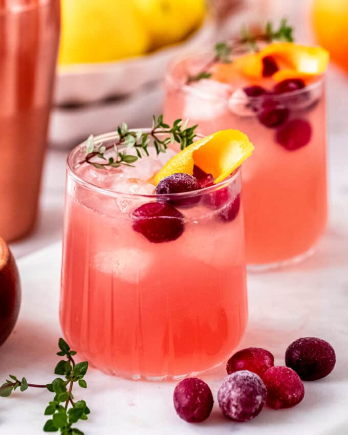 two glasses filled with a mixed drink made of cranberry and orange juice and whiskey