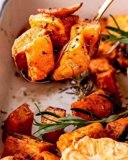 These Garlic Roasted Sweet Potatoes are a fantastic savory side dish for your family dinner or holiday meal. Diced sweet potatoes are seasoned and roasted with fresh herbs along with a head of garlic, which adds amazing flavor!