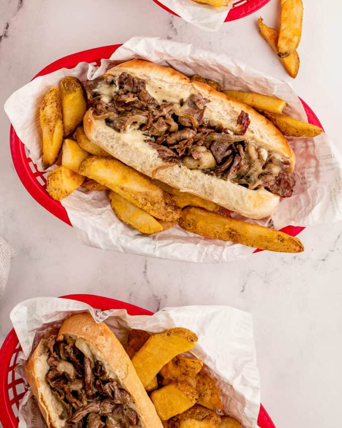 cheesesteaks with fries in takeout baskets