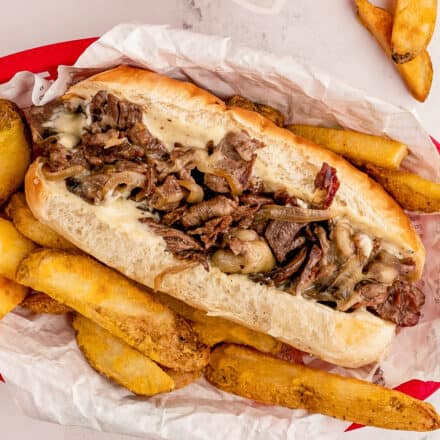 cheesesteak sandwich with fries in takeout basket
