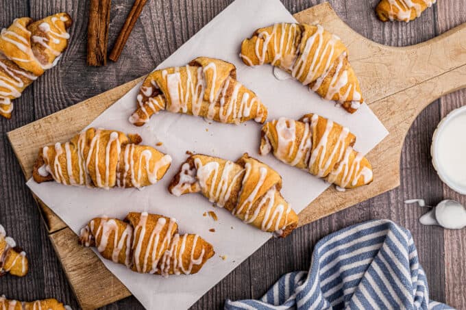 several cinnamon crescent rolls on wooden cutting board with parchment