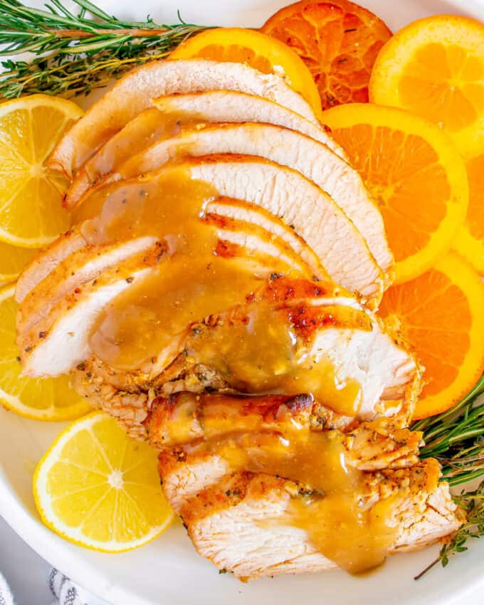 turkey slices on platter with oranges, lemons, and herbs, drizzled with gravy