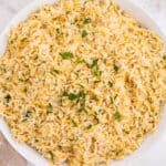 overhead view of rice pilaf in white bowl garnished with parsley
