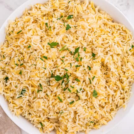 overhead view of rice pilaf in white bowl garnished with parsley