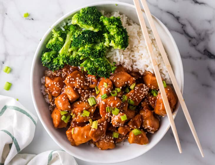 white bowl with sesame chicken and broccoli