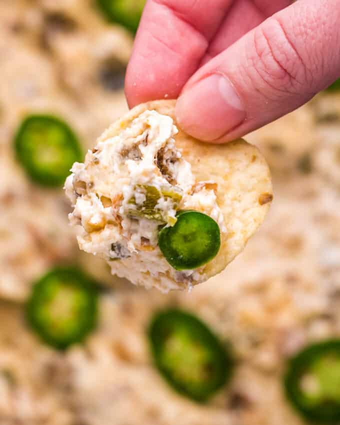 close up of holding a tortilla chip with jalapeno popper dip