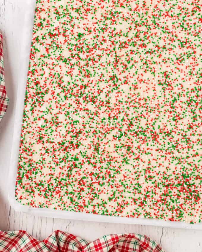 sugar cookie fudge in baking pan sprinkled with red and green sprinkles