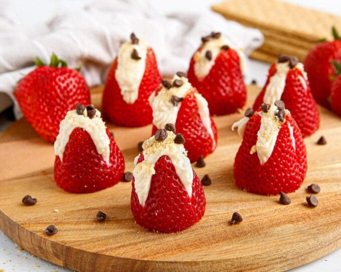 round cutting board with several stuffed strawberries on top