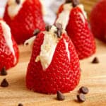 wooden cutting board with cheesecake stuffed strawberries