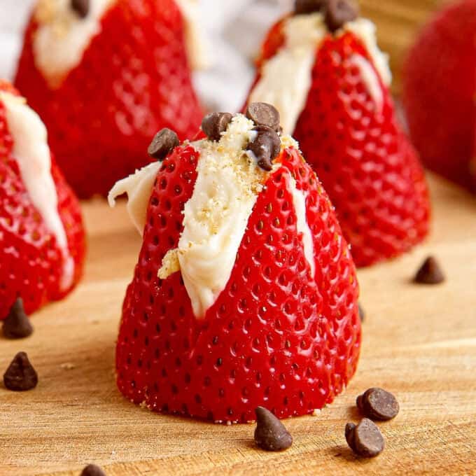 wooden cutting board with cheesecake stuffed strawberries