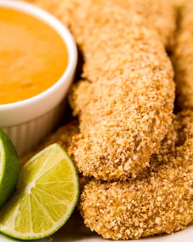 close up view of cashew chicken tenders with dipping sauce and lime wedge