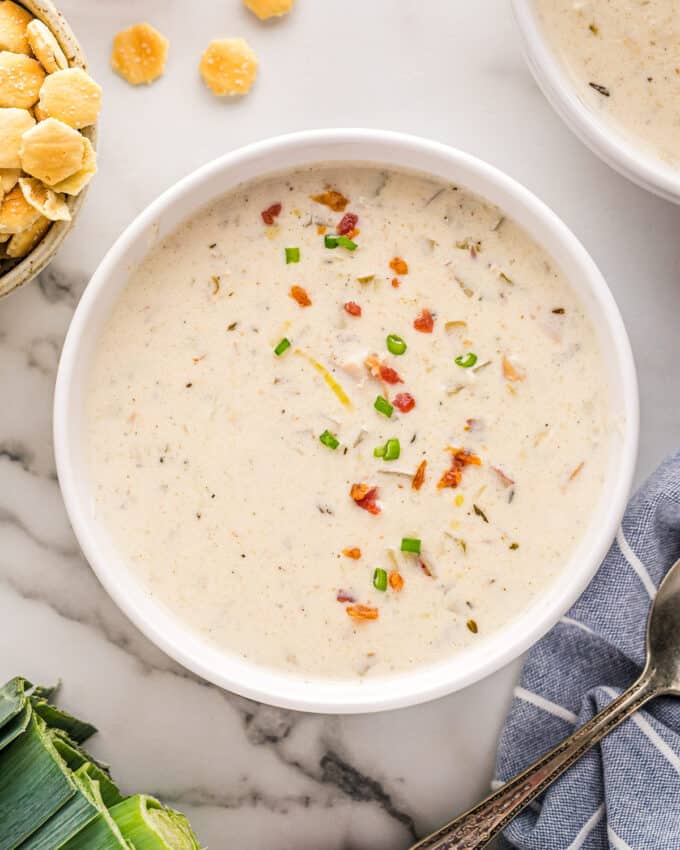 overhead view of a white bowl of clam chowder garnished with bacon and fresh parsley