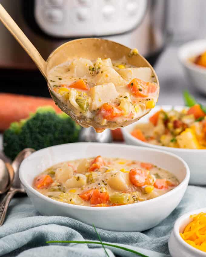 ladling vegetable soup into white bowl