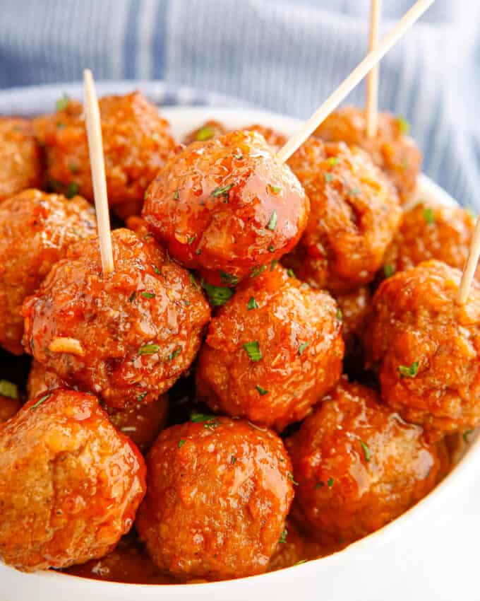 spearing a toothpick into a honey buffalo meatball that's in a white bowl
