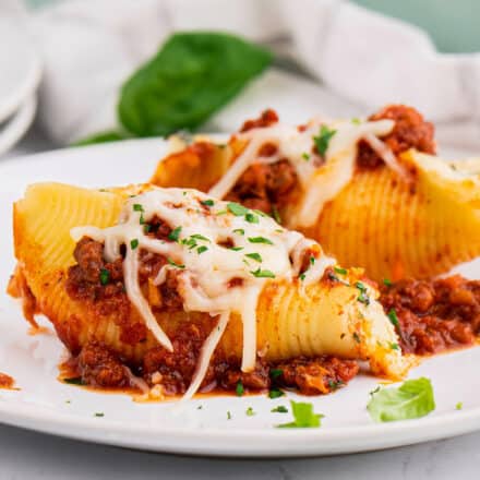 two lasagna stuffed shells on white plate with minced parsley
