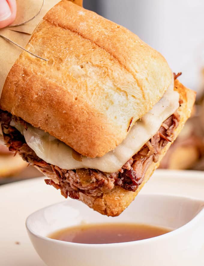 These Slow Cooker French Dip Sandwiches are made with ultra tender roasted beef, melted provolone cheese, soft hoagie bread, and dipped into an amazing au jus sauce. Perfect cold weather comfort food for the whole family!
