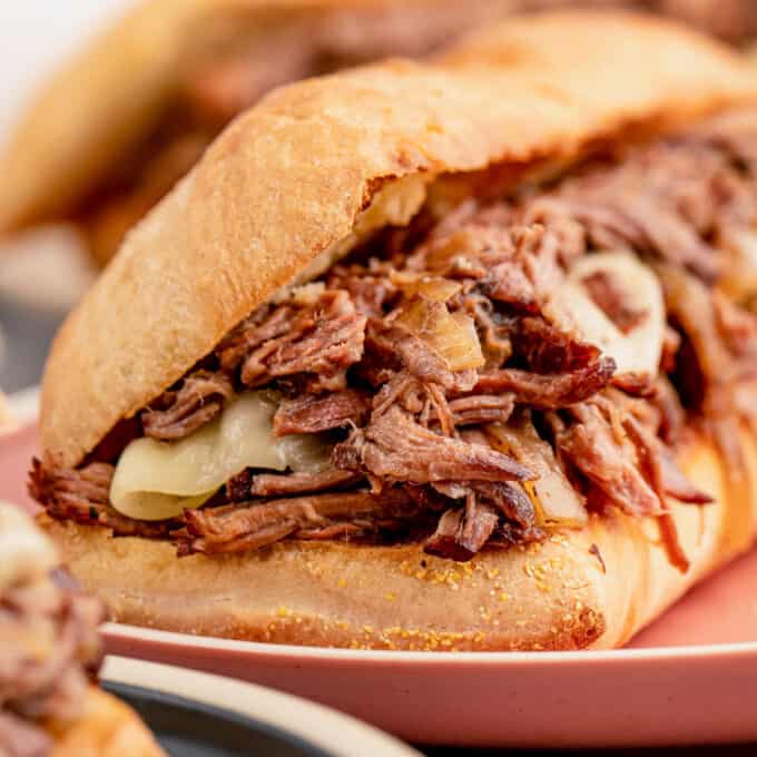 side view of a french dip sandwich showing the shredded beef and melted cheese