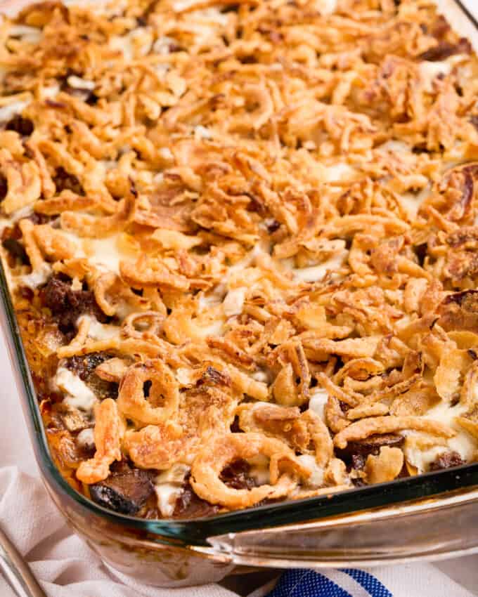 close up photo of a glass casserole dish filled with rice casserole with beef, mushrooms, french onions