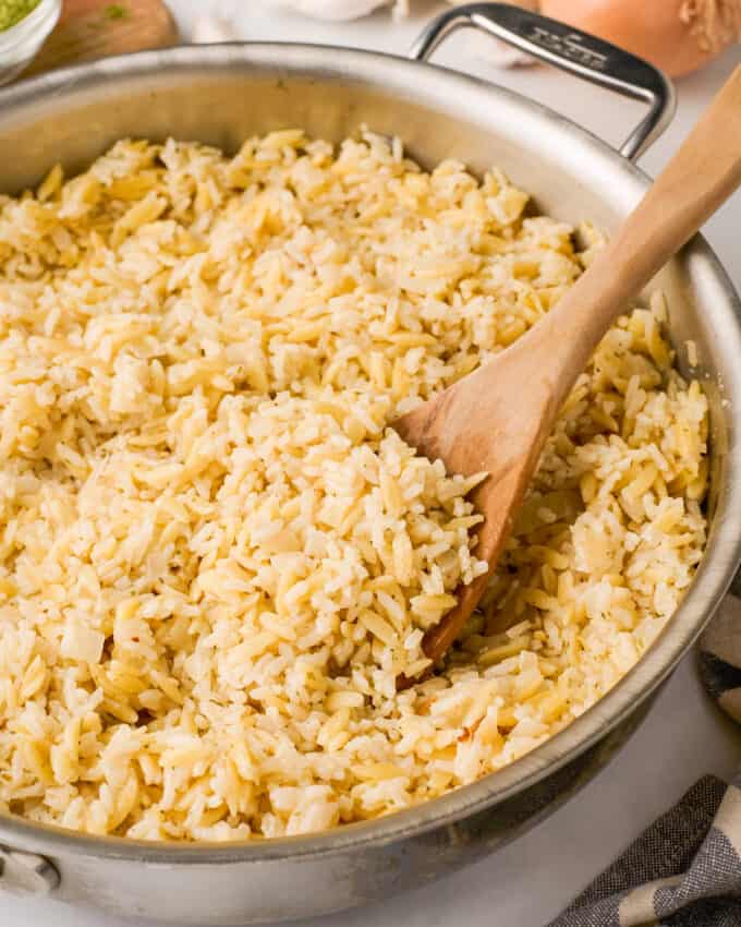 serving parmesan rice pilaf from the skillet with a wooden spoon