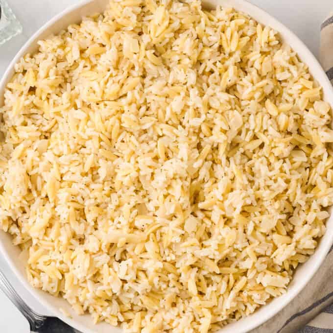 overhead photo of a large white serving bowl filled with cheesy rice pilaf