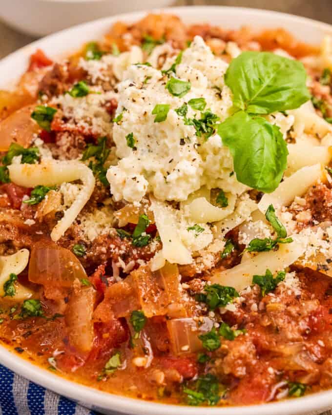 close up photo of a bowl of lasagna soup with an herbed ricotta dollop on top with fresh basil