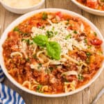 white bowl of lasagna soup topped with ricotta cheese and fresh basil