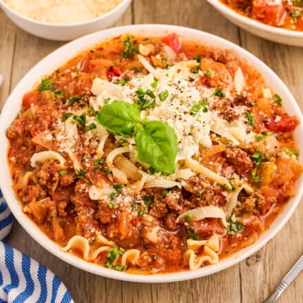 white bowl of lasagna soup topped with ricotta cheese and fresh basil