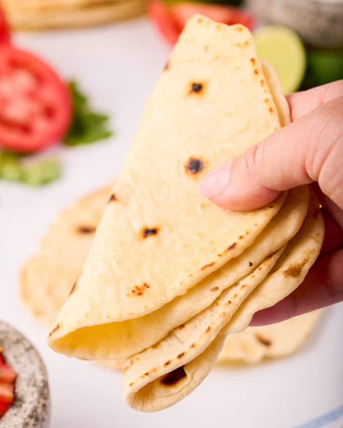 holding two flour tortillas made from scratch