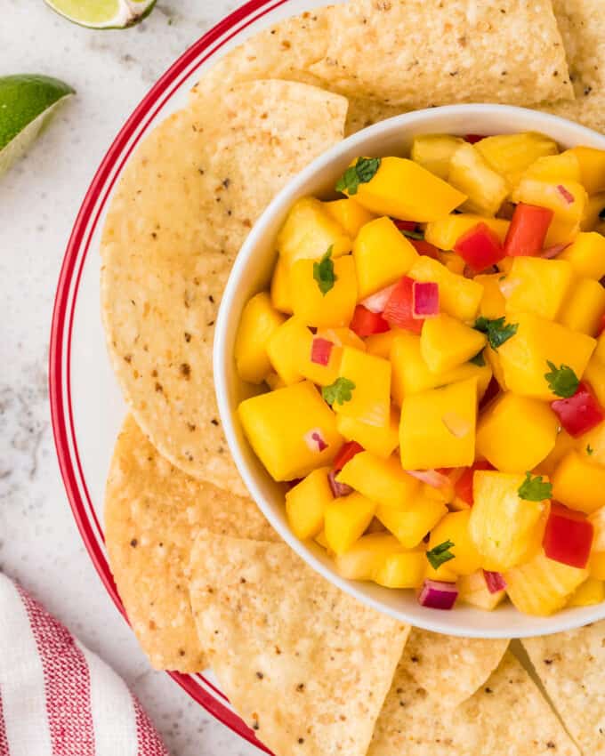 overhead view of a bowl of mango salsa surrounded by tortilla chips