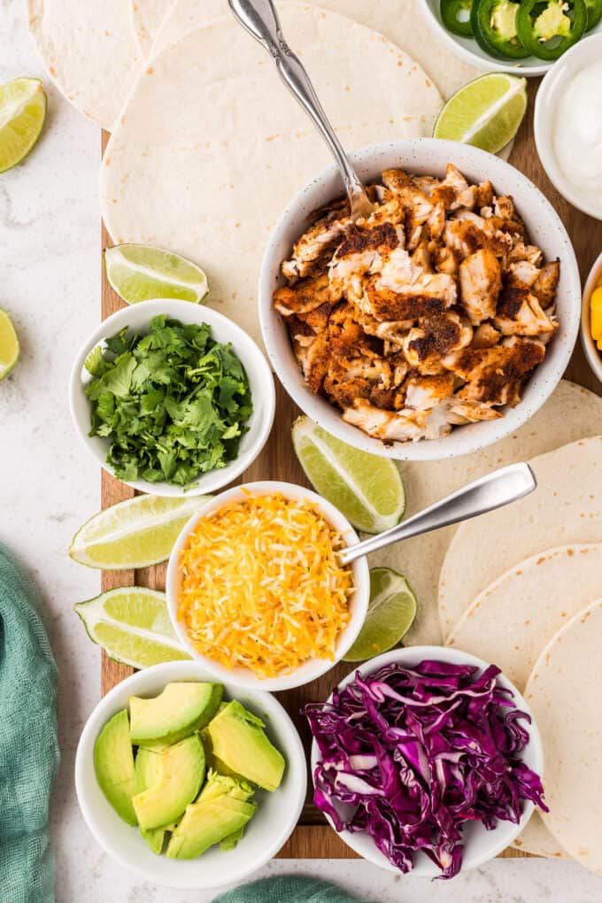 fish taco bar set up with various small bowls and flour tortillas