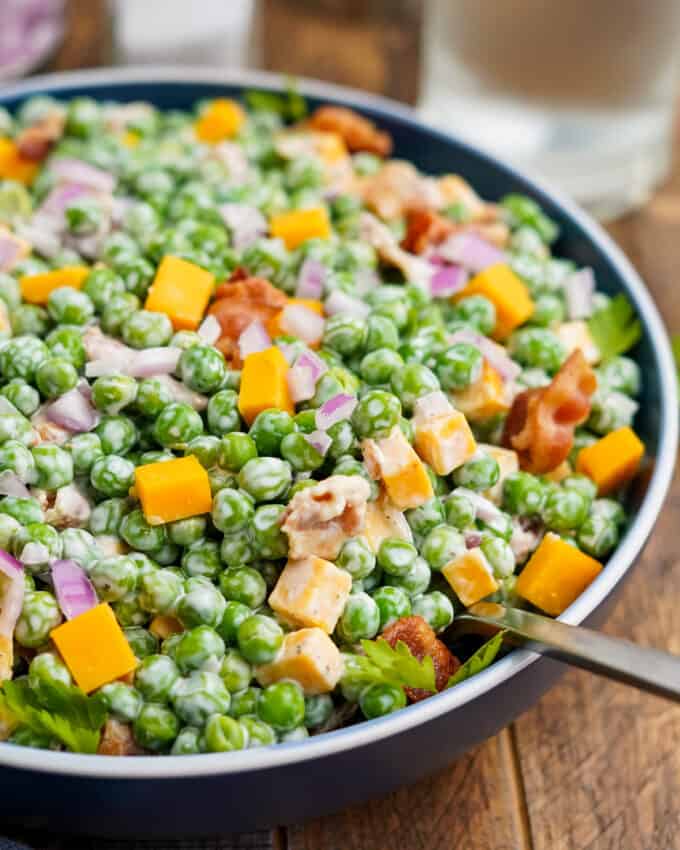 serving bowl of pea salad with a serving spoon in it