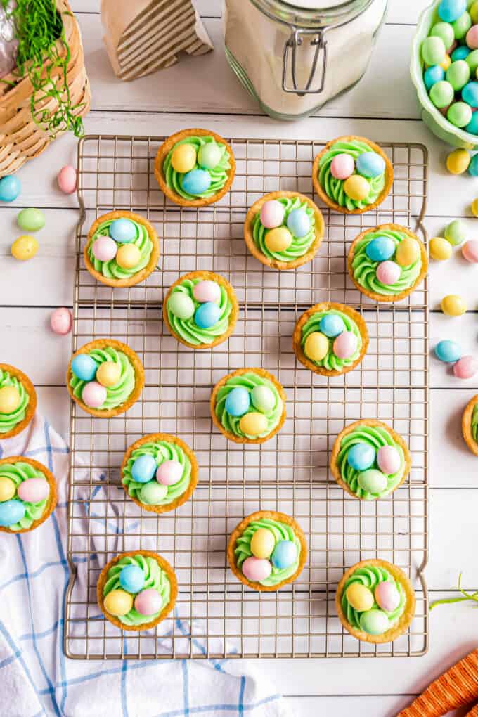 overhead photo of a wire cooling rack topped with many decorated easter basket cookie cups