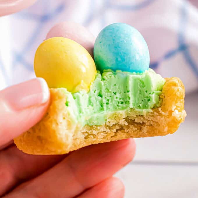 cookie cup filled with frosting and candy eggs with a bite taken out of it to show the center