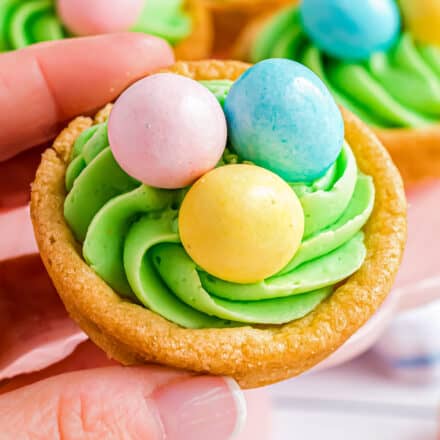 holding a sugar cookie cup filled with frosting and Easter egg candies