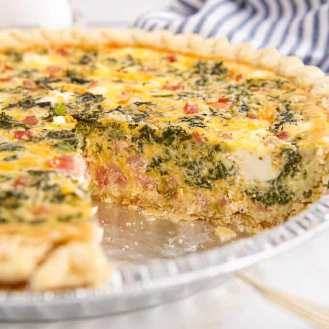 quiche in a pie pan with a slice taken out