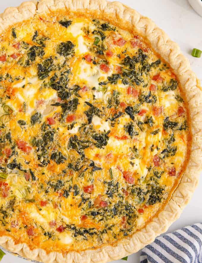 This quiche recipe is loaded with savory flavors like ham, cheese, spinach, cream cheese, green onions and more! Plus it can be made with a homemade OR store-bought pie crust, can be prepped ahead, and is perfect for a holiday brunch!